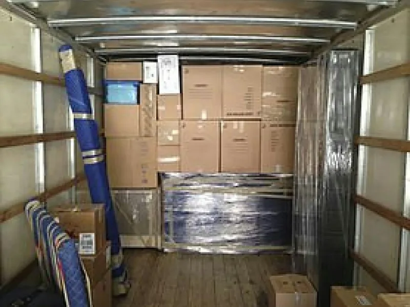 Packed household goods being loaded into a moving truck for house shifting in Kakinada