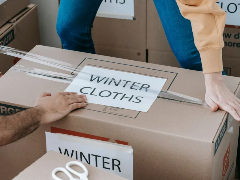 Movers labelling and sealing boxes during home shifting