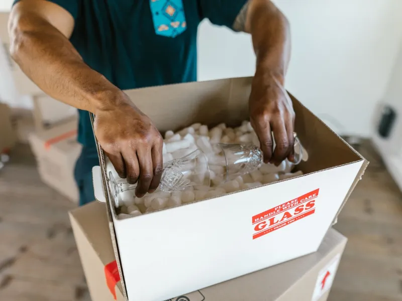 Trained mover carefully packing glassware into a labelled box