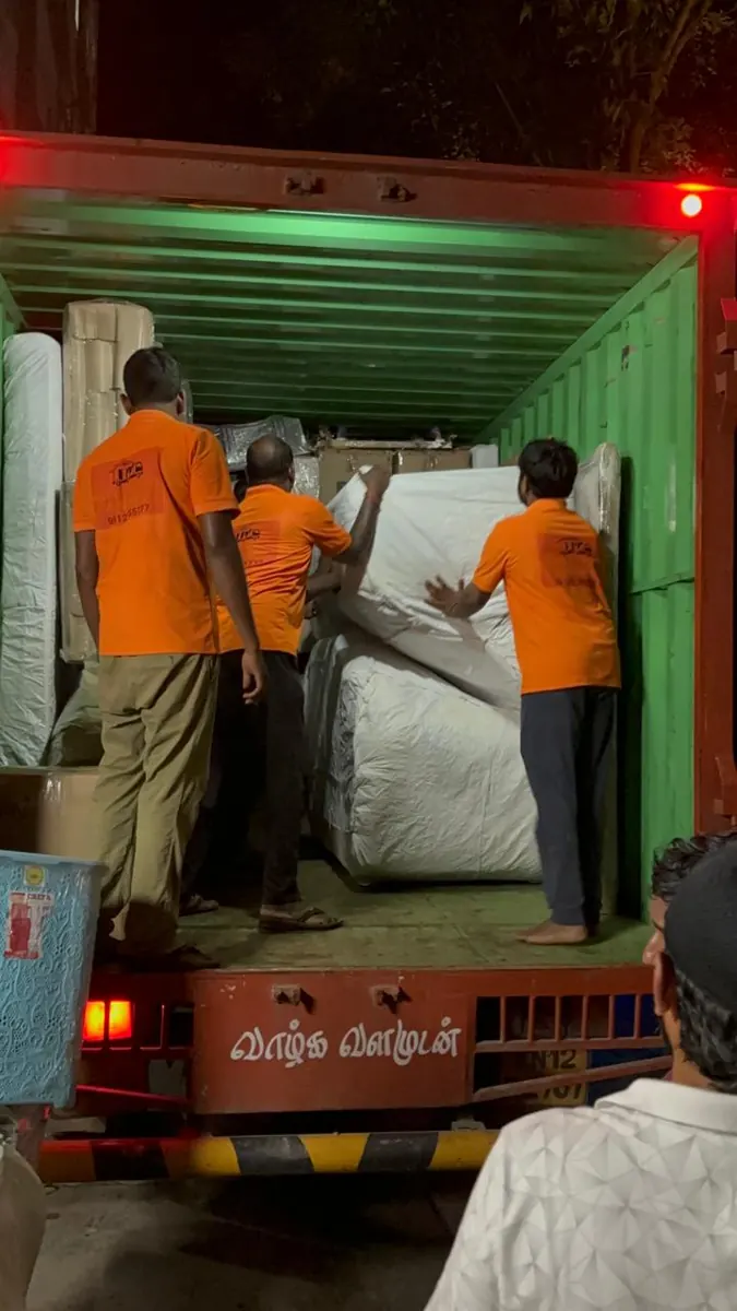 Hanu Packers and Movers team loading wrapped mattresses and furniture into a container truck for intercity shifting from Kakinada